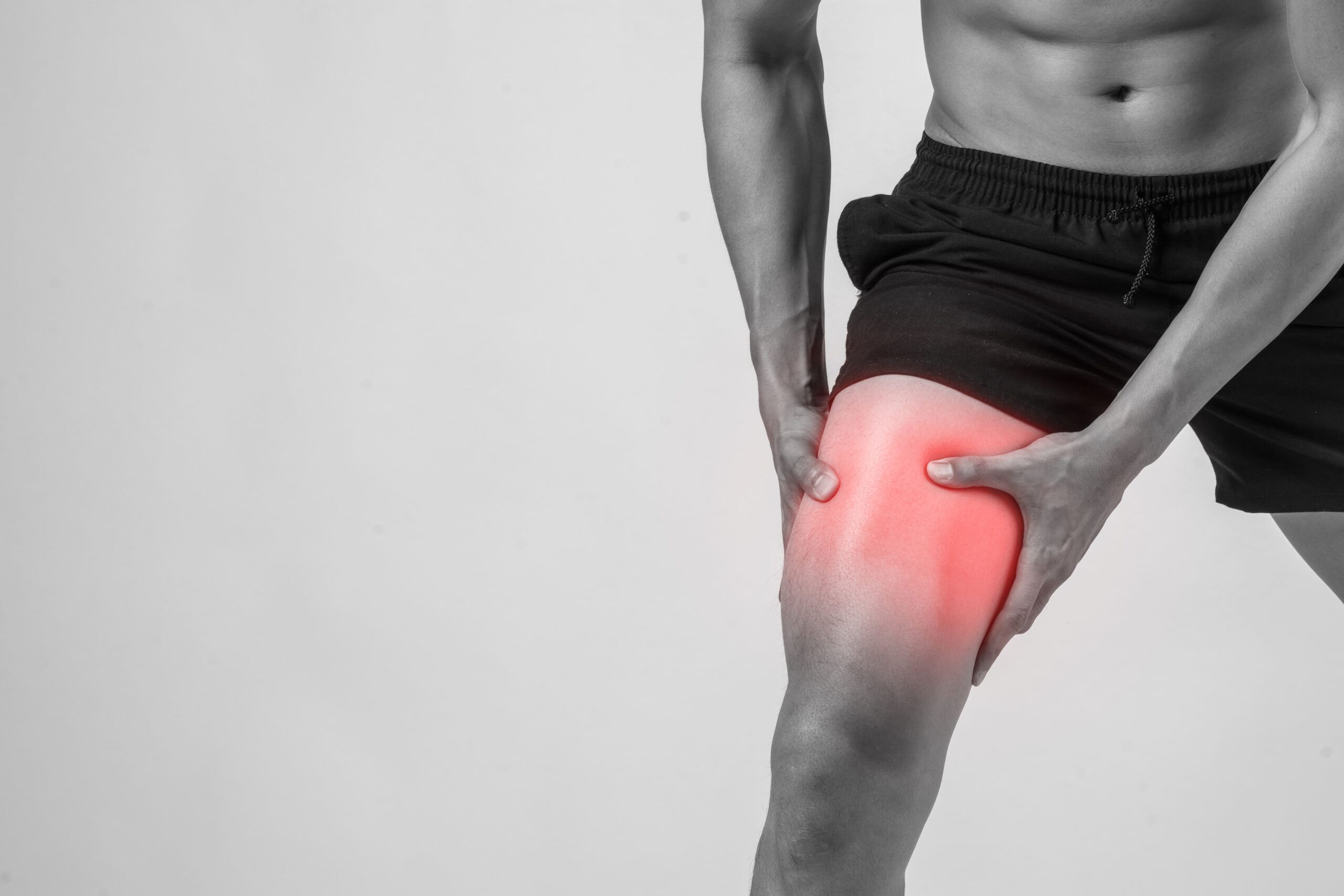 Young sport man with strong athletic legs holding knee with his