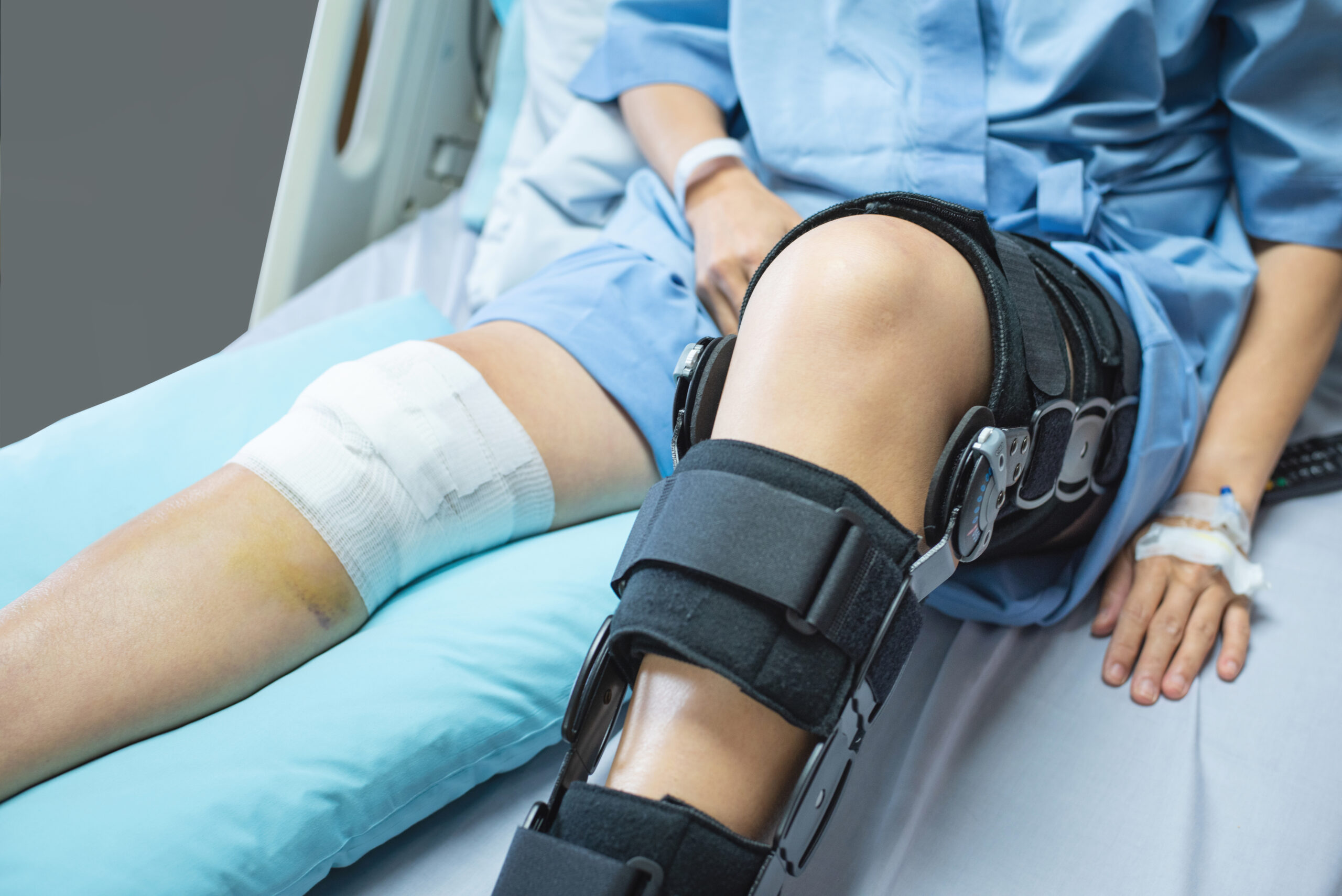 Asian woman patient with bandage compression knee brace support injury on the bed in nursing hospital.healthcare and medical support.